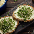 бутерброды с творожным сыром и микрозеленью кресс-салата лежат на разделочной доске