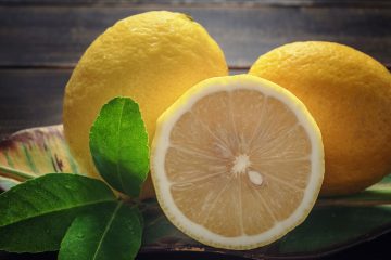 лимоны с зелеными листочками на темном фоне