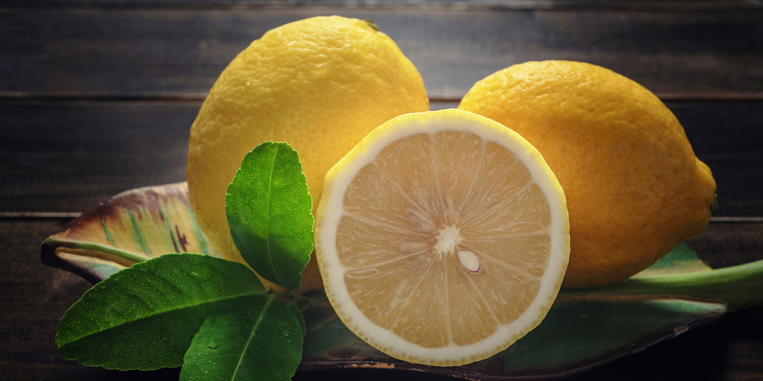 лимоны с зелеными листочками на темном фоне