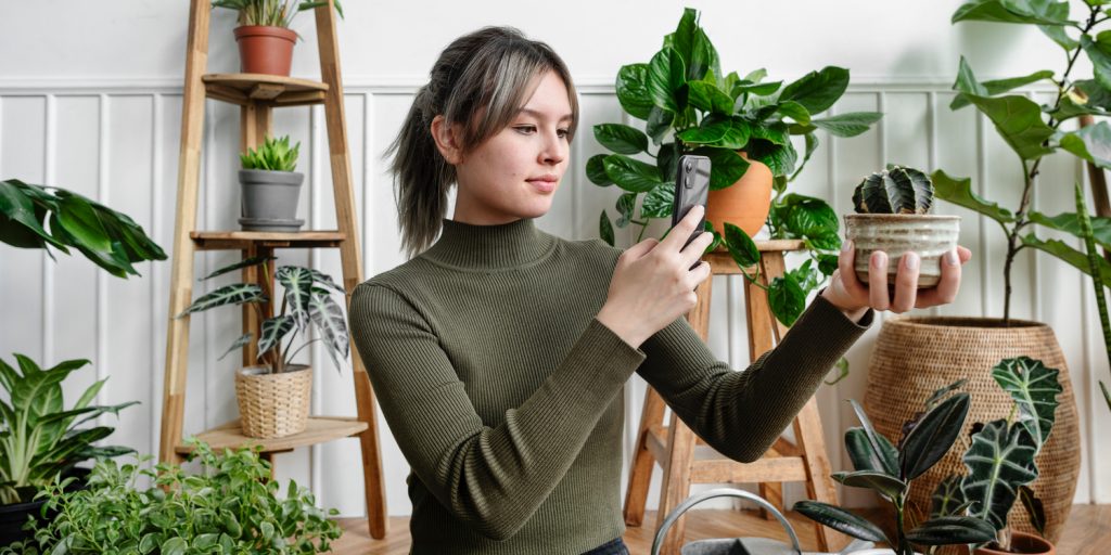 девушка смотрит на растение в горшке