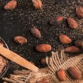 Какао-бобы, мешковина, порошок какао в круглой миске и деревянная ложка