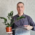 Игорь Шелехов держит растение в цветочном горшке и коврик для обогрева растений из карбоновой пасты собственного производства