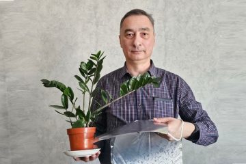 Игорь Шелехов держит растение в цветочном горшке и коврик для обогрева растений из карбоновой пасты собственного производства