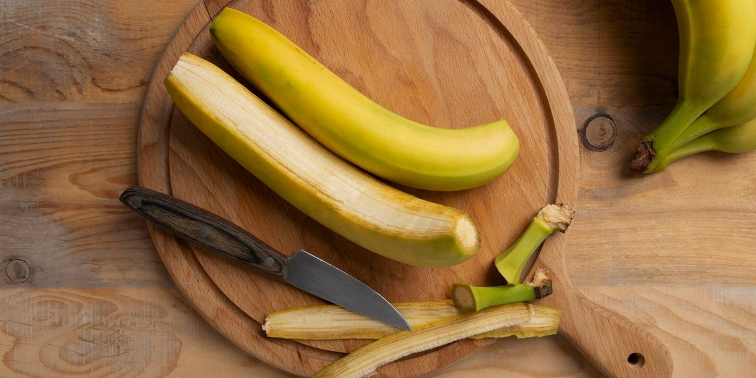 два банана и нож лежат на разделочной доске
