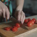 Женщина нарезает томаты на разделочной доске, крупным планом