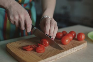 Женщина нарезает томаты на разделочной доске, крупным планом