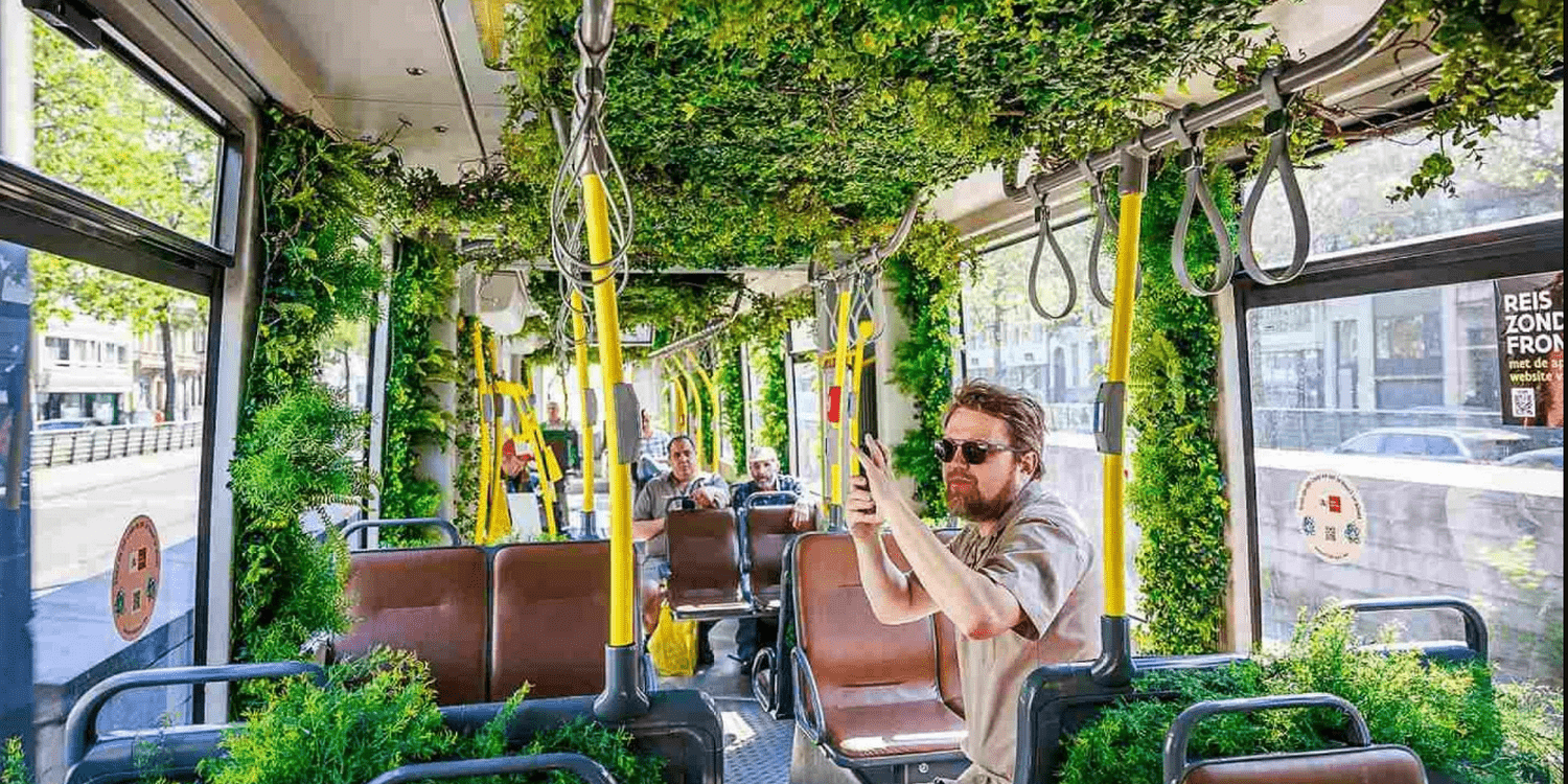 мужчина фотографирует на телефон вагон трамвая с растениями
