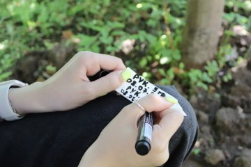 Руки подростка, подписывающего чёрным маркером бирку что бы пометить растения