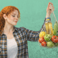 Девушка держит авоську со свежими овощами и фруктами