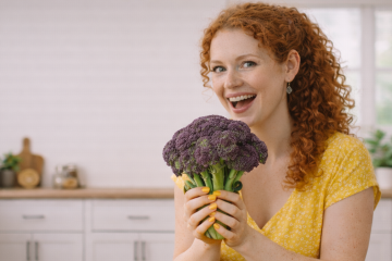 Девушка в желтом платье держит в руках соцветие брокколи фиолетового цвета