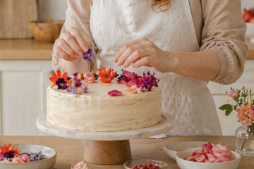 Девушка украшает торт съедобными цветами на кухне