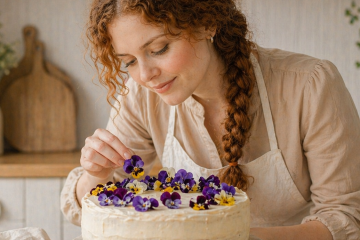 Девушка украшает торт цветами анютины глазки
