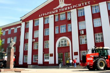 Здание Алтайского государственного аграрного университета, у входа стоит большой красный трактор