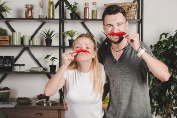 Молодая пара прикладывает красный перец вместо усов
