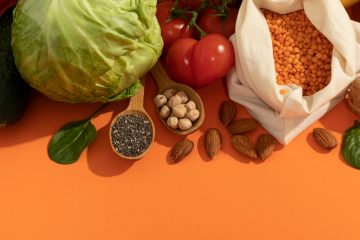 На оранжевой поверхности лежат: картошка, капуста, помидоры, грецкие орехи, миндаль, огурцы