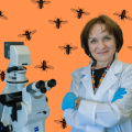 Женщина-учёный в белом халате стоит рядом с современным электронным микроскопом.
