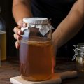Девушка ставит на стол банку с чайным грибом