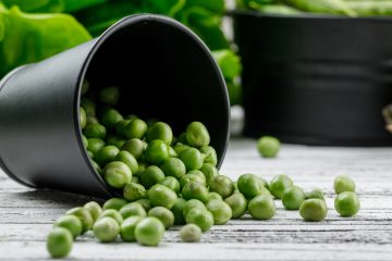 На столе лежит ведёрко, из которого высыпался горох