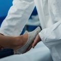 Врач в белом халате осматривает женщину с больной ногой