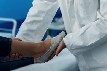 Врач в белом халате осматривает женщину с больной ногой