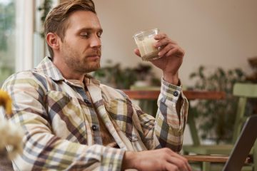 Мужчина пьет какао и работает с ноутбуком