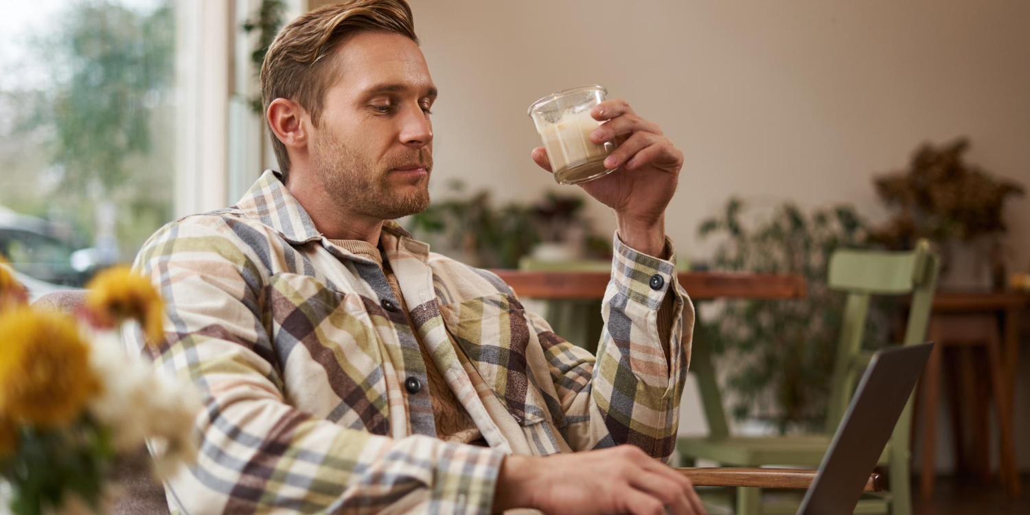 Мужчина пьет какао и работает с ноутбуком