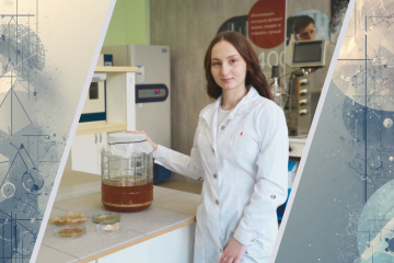 Молодая женщина учёный в белом халате стоит в лаборатории. Рядом на столе стоит большая банка с чайным грибом и лежат образцы в чашках Петри