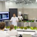 В аудитории презентация салата, выращенного при помощи гидропоники. Люди в белых халатах