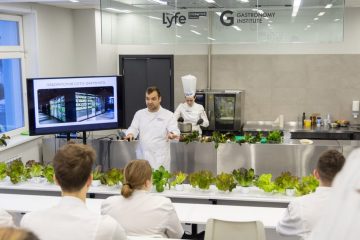 В аудитории презентация салата, выращенного при помощи гидропоники. Люди в белых халатах