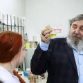 Ученый демонстрирует колбу с цветной жидкостью