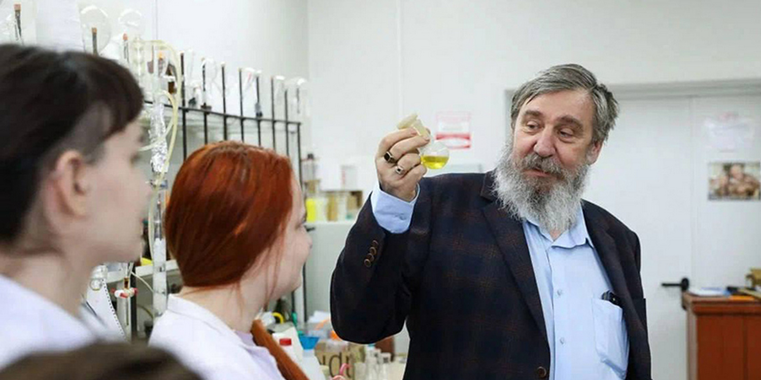 Ученый демонстрирует колбу с цветной жидкостью