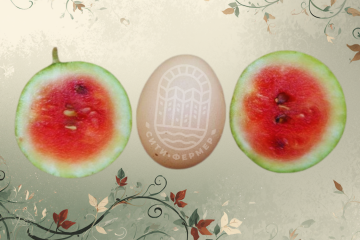 Разрезанный на две части миниатюрный арбуз лежит рядом с куриным яйцом